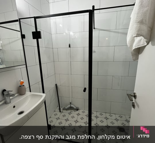 מקלחון זכוכית עם דלתות שחורות ומגב רצפה